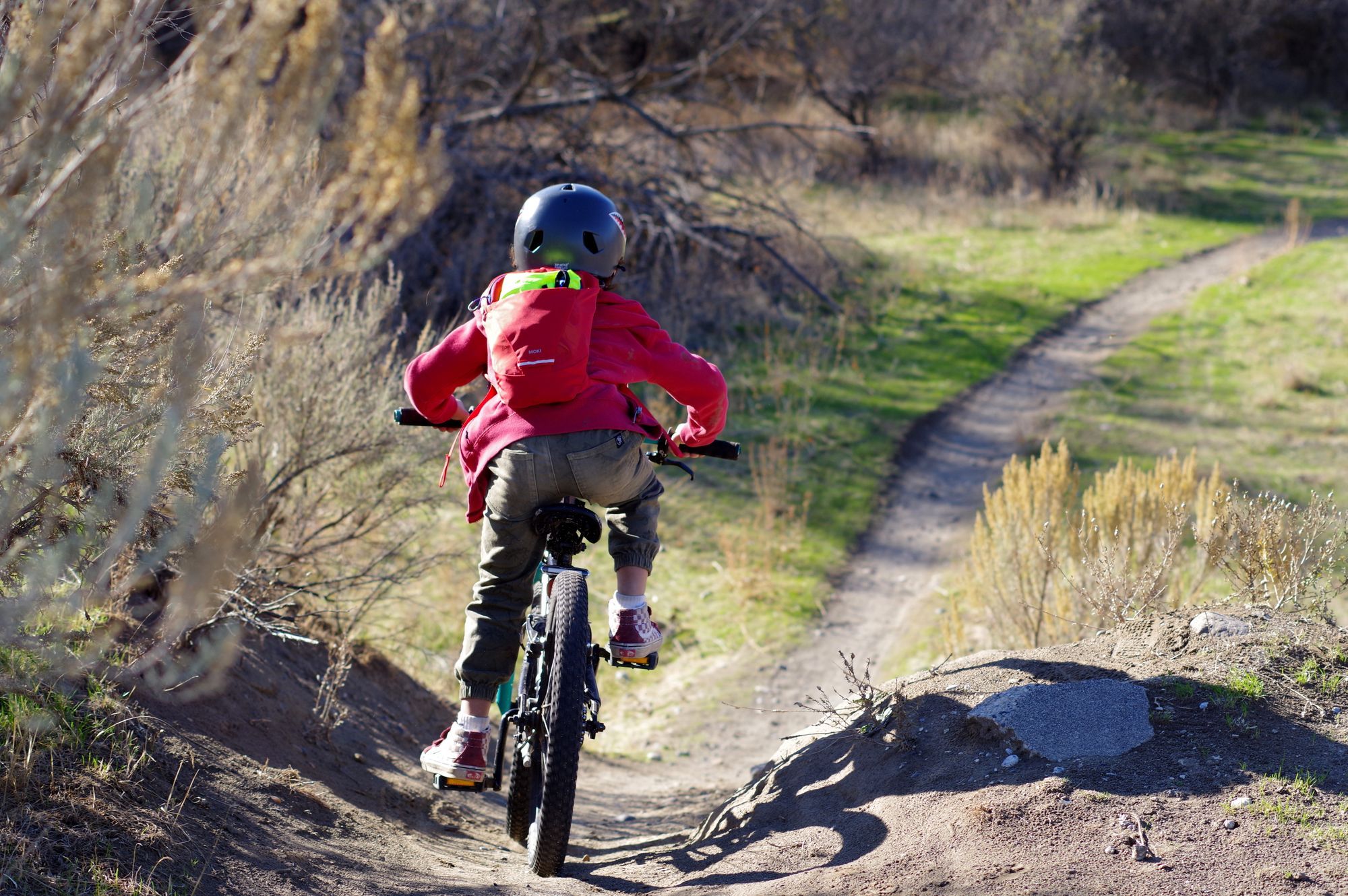 Image shows child riding a bike on a trail at Chamna