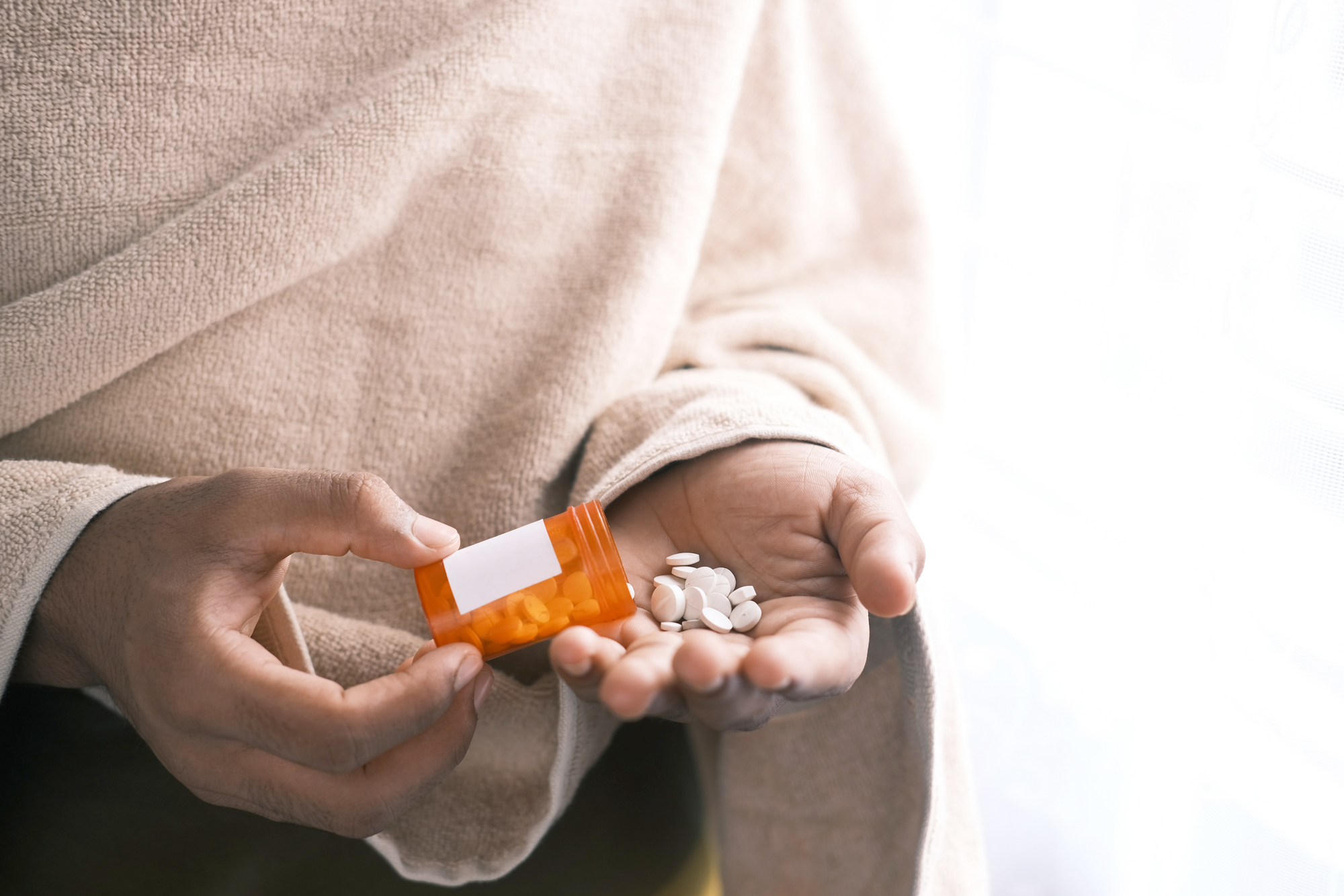 Photo of someone emptying a pill bottle into their hands