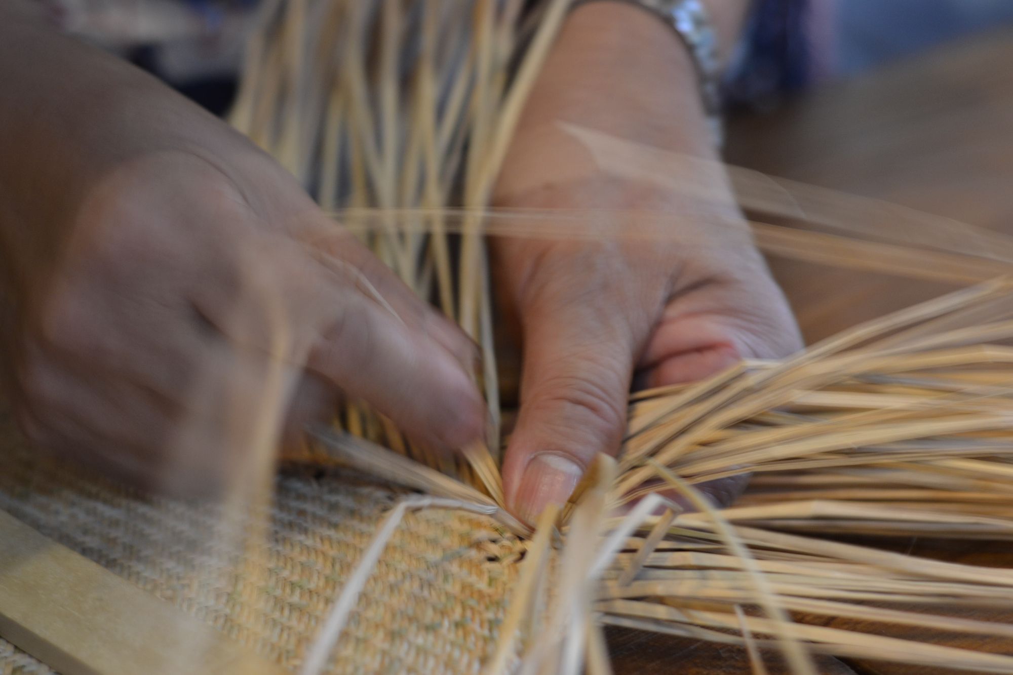 Image of hands weaving grass