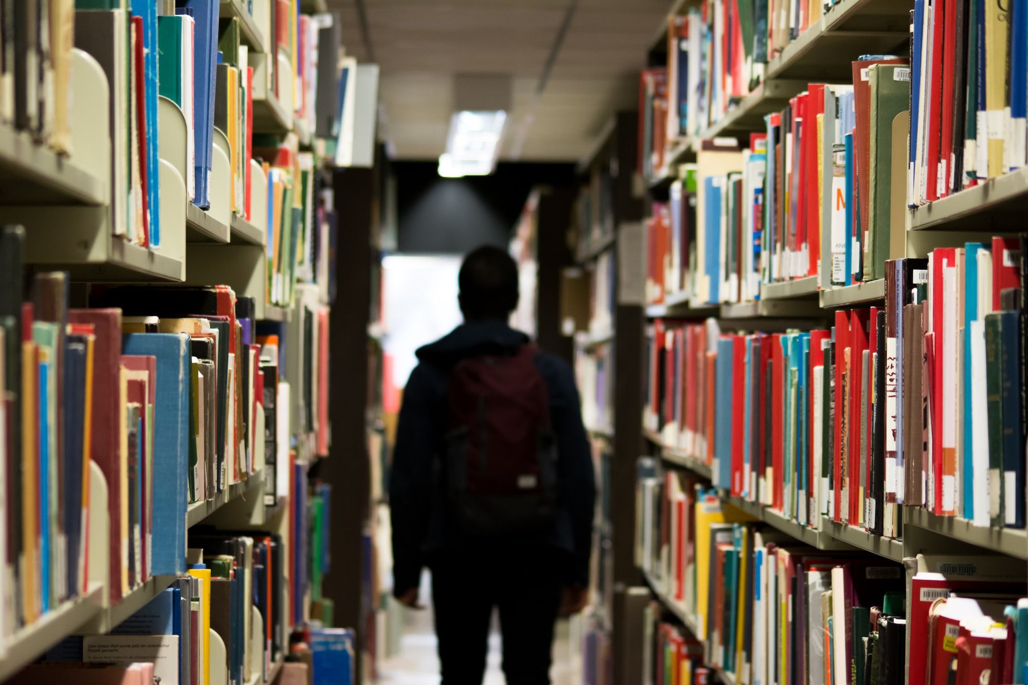 Image of a student walking between stacks of books in a library