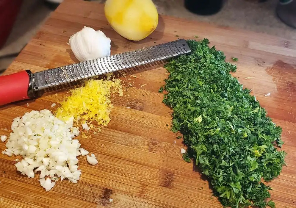 Cutting board with parsley, onion, garlic, and lemon zest