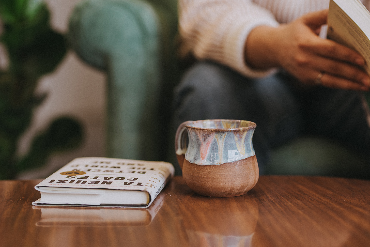 Image of someone reading in front of a low table with a book and a mug