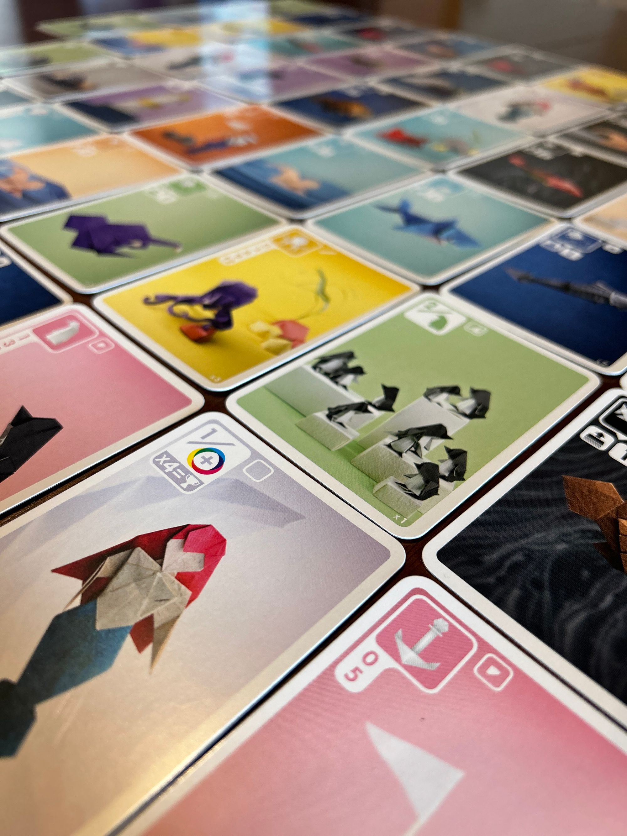 Closeup of cards from the game Sea Salt and Paper, featuring colorful images of origami