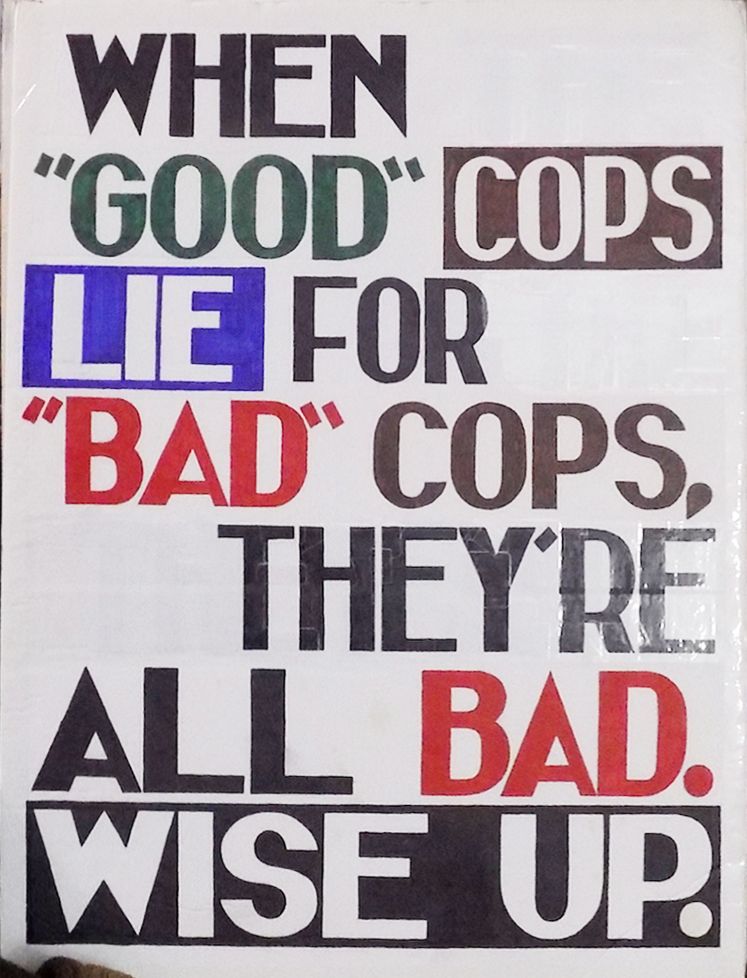 Sign saying: "When 'good' cops lie for 'bad' cops, they're all bad. Wise up."