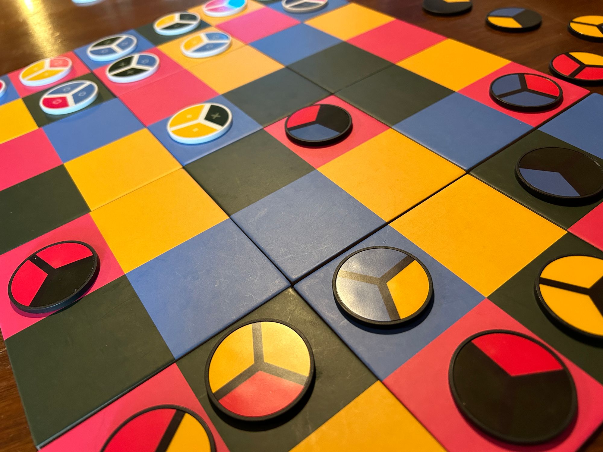 An Image of a colorful board game with colorful tiles and checkers.