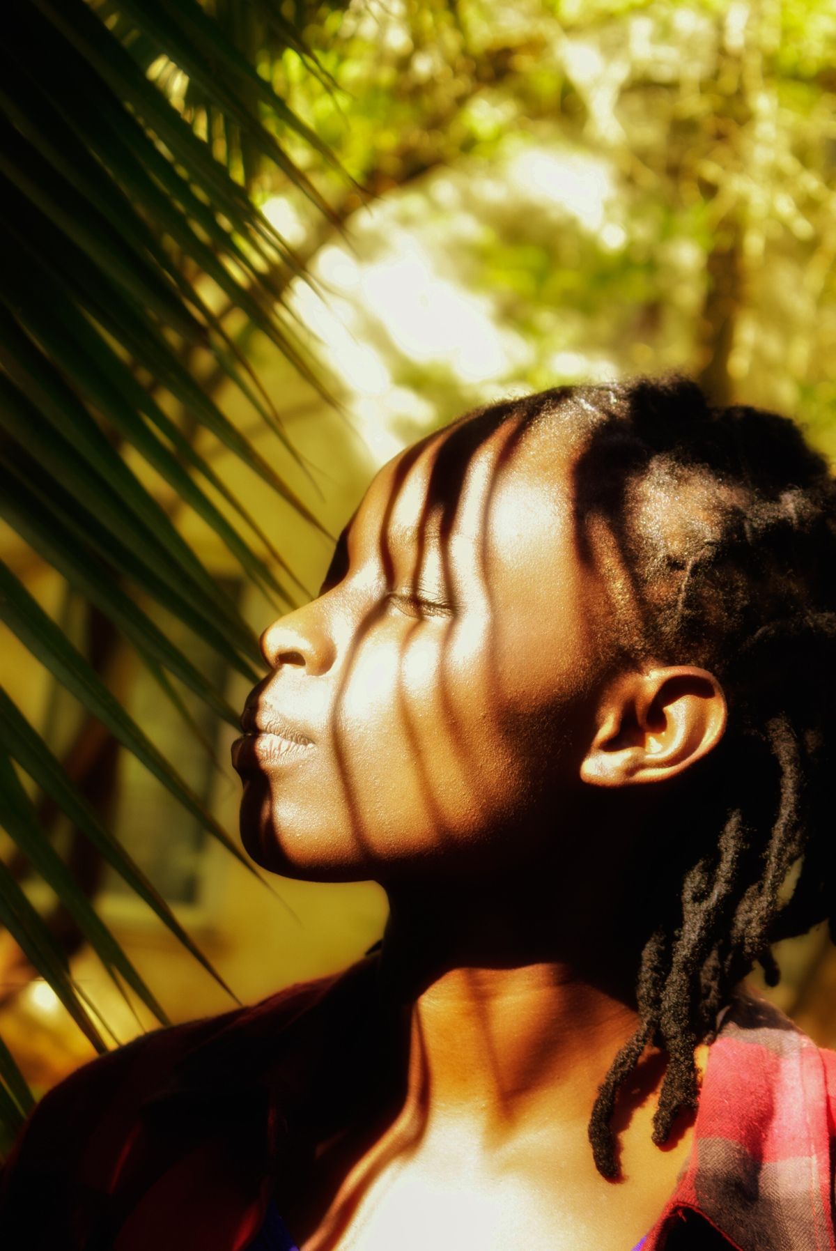 An image of a black woman with black hair, there are shadows being cast on their face.