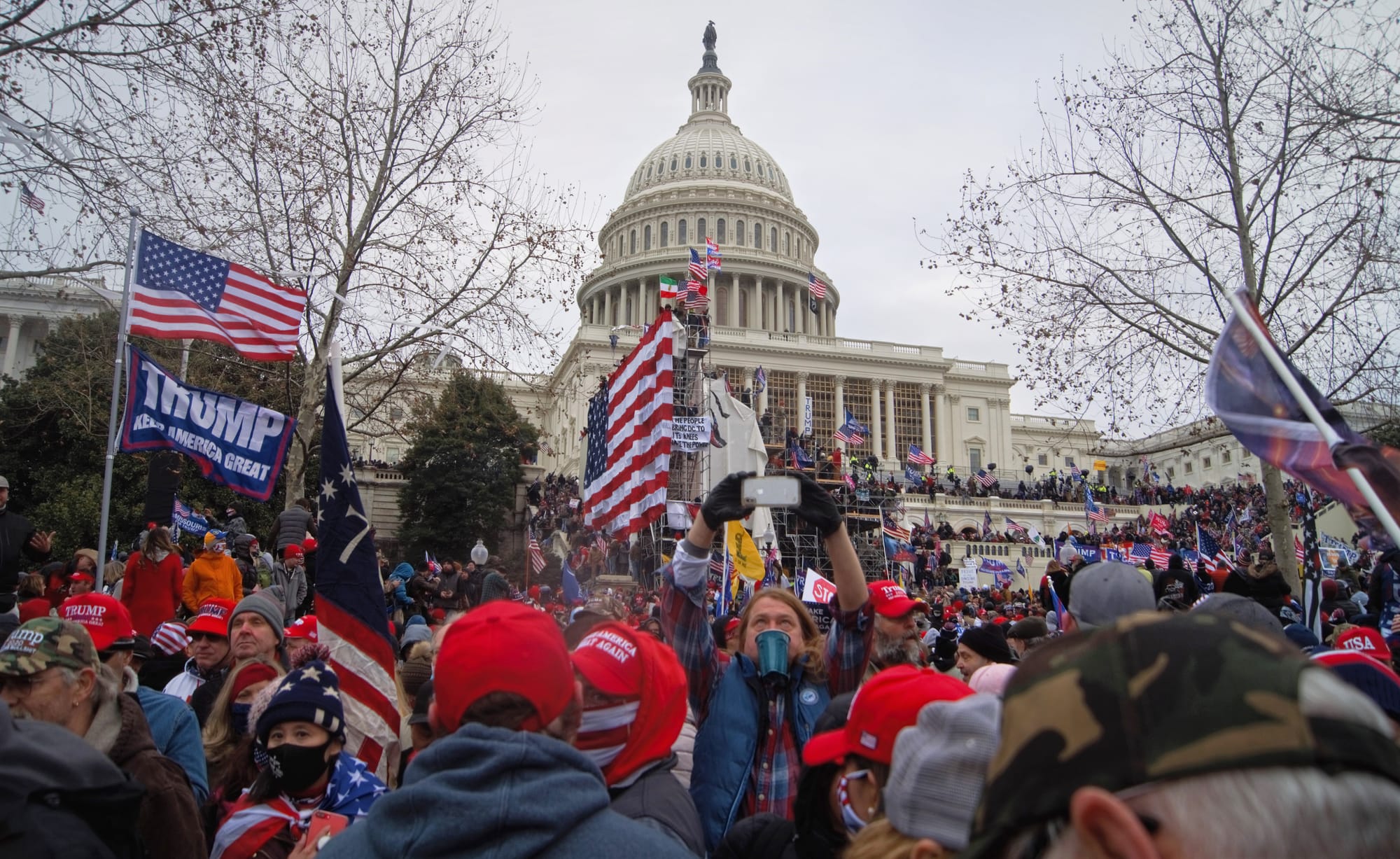 Rioters outside the US Capitol building holding US flags and "Make America Great Again" flags